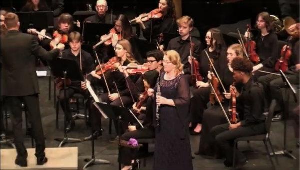 woman preparing to play obeo while orchestra plays in background