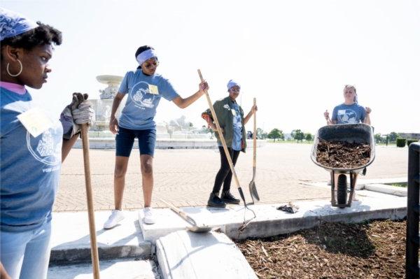 Volunteers and 学生 spread wood chips around landscaping around the James Scott Memorial Fountain at Belle Isle Park in Detroit.