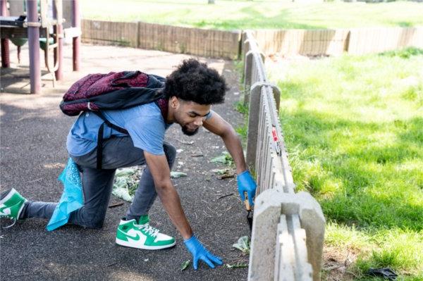 A student from University Prep Science and 数学 High School in Detroit pulls weeds from a playground at Belle Isle Park.