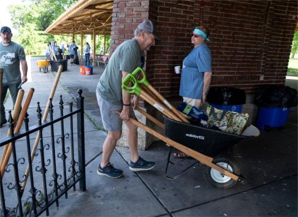 丹Sippel, executive director with the West Michigan Tourist Association, hauls a wheelbarrow filled with tools for Michigan Cares for 旅游's cleanup project on Belle Isle Park. 