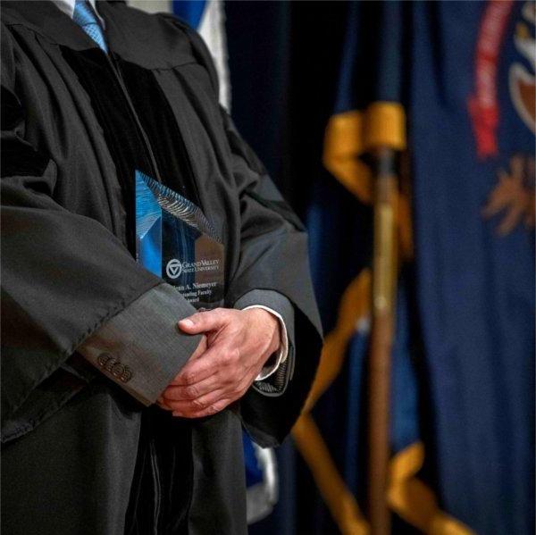 faculty member in academic regalia holding an award